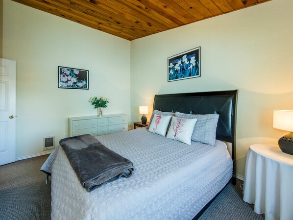 A neatly made bed with a grey blanket, a headboard, and decorative pillows. - 2-story dog-friendly home with beach access, Ping-Pong table, & grill (Manzanita)