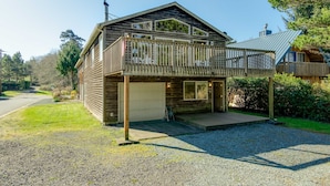 Una casa a due piani in legno con un balcone, un garage e un vialetto sterrato.