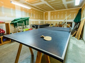 Ein Tischtennis-Tisch mit Schläger in einem Raum mit unbehandelten Wänden und verstreuten Gegenständen.