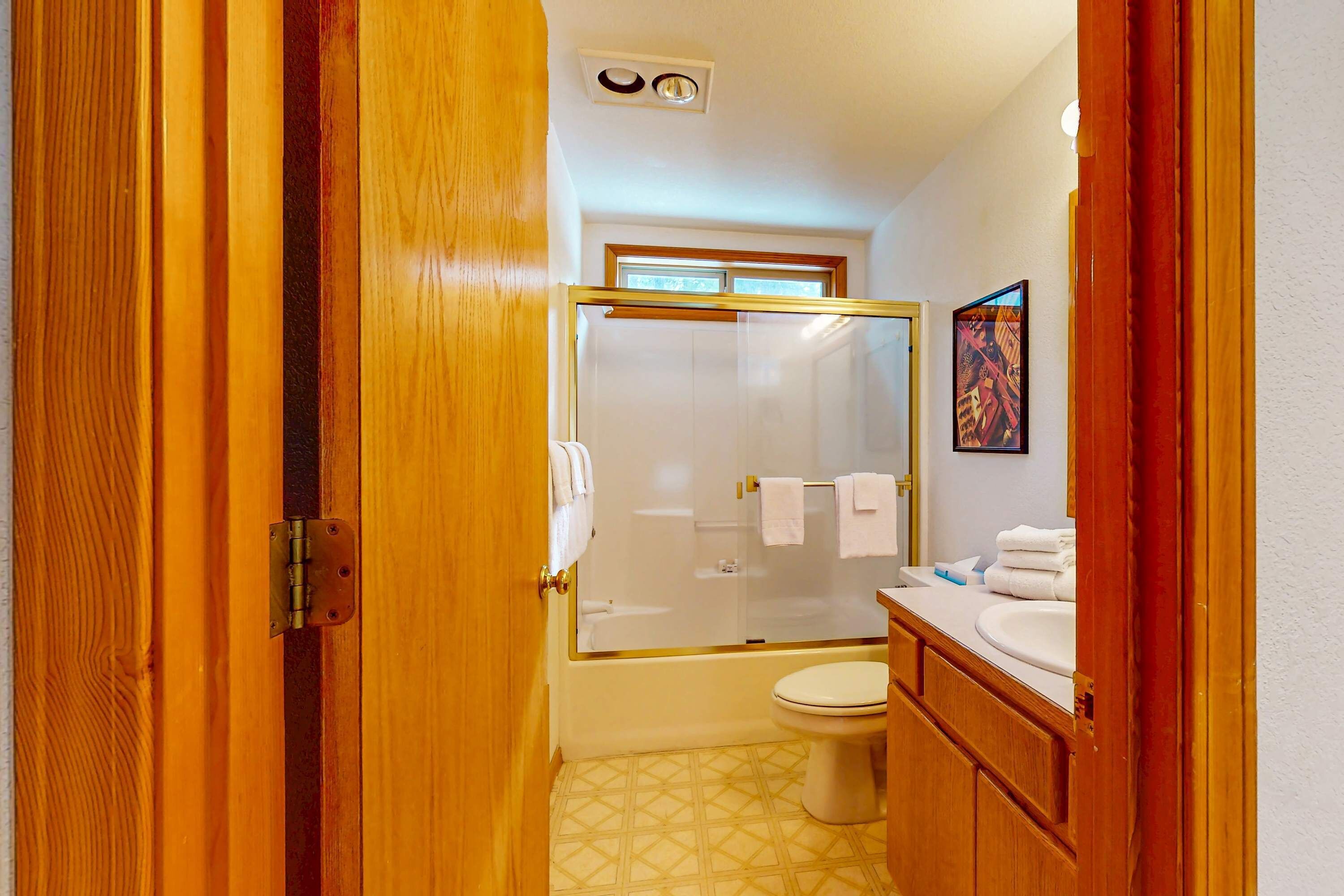 A bathroom with a glass shower enclosure, a toilet, a sink, and a mirror.