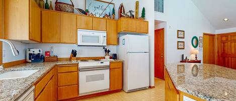 A kitchen with wooden cabinets, a microwave, a refrigerator, a stove, and a sink.