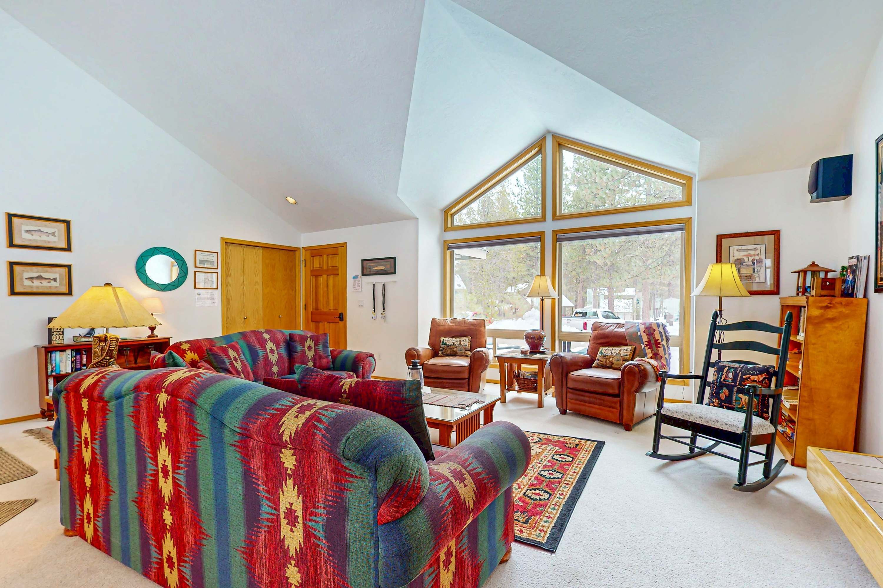 A living room with a sofa, chairs, a rocking chair, a coffee table, and a rug.