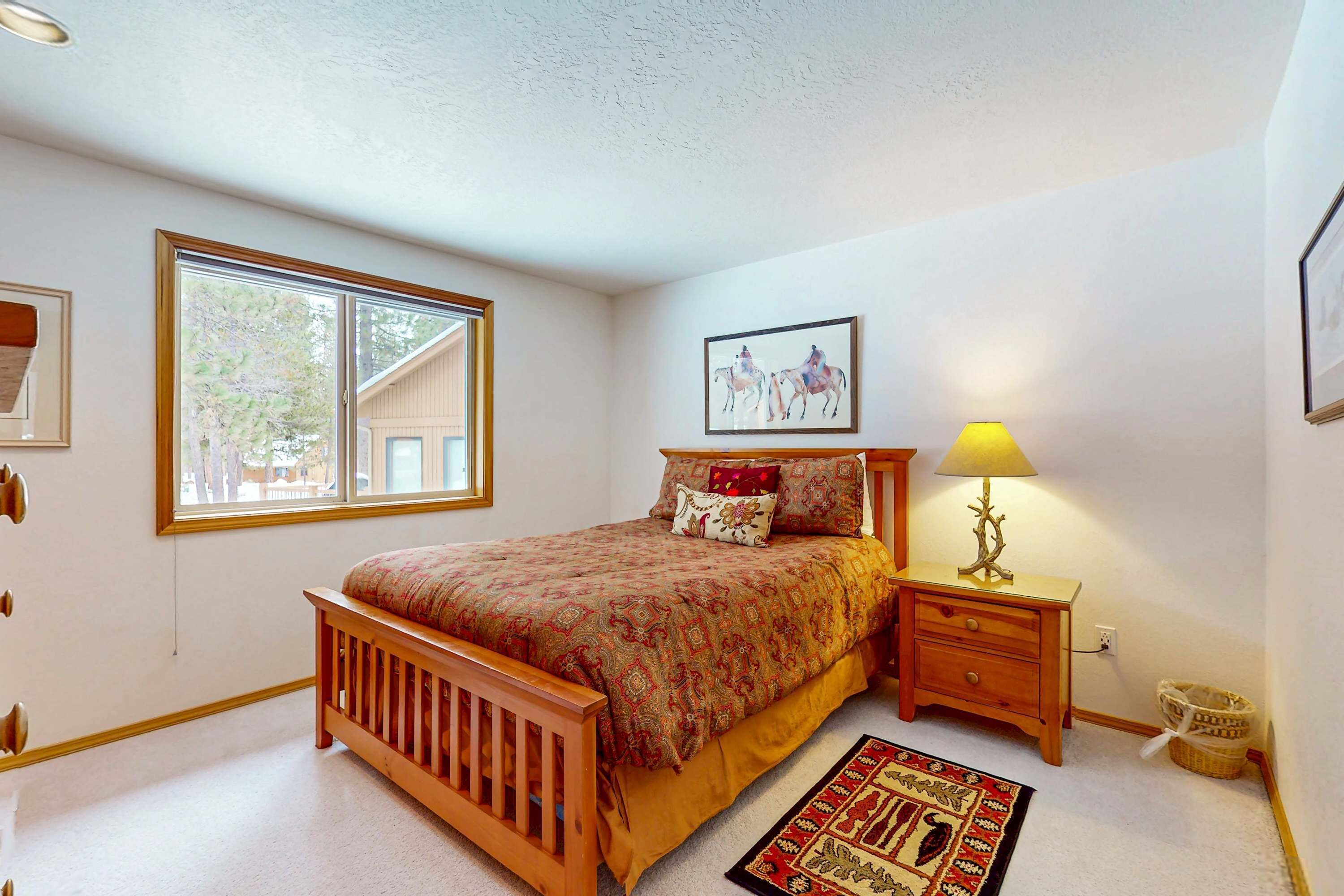 Une chambre à coucher avec un lit, une table de chevet, une lampe, une fenêtre et un tapis.