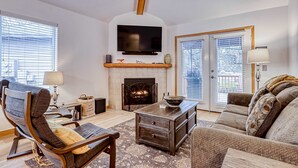 A living room with a fireplace, a flat-screen TV, a sofa, a chair, and a coffee table. - Spacious getaway near town with private hot tub, pool access, and fast WiFi (Eagle Crest)