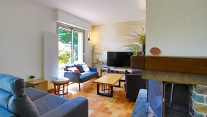 A living room with a sofa, a coffee table, a TV, and a fireplace.