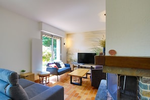 Ein Wohnzimmer mit einer Couch, einem Couchtisch, einem Fernseher und einem Kamin.