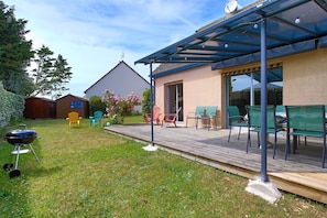 Eine überdachte Terrasse mit Sitzgelegenheiten im Freien, einem Grill und einem Holzboden.