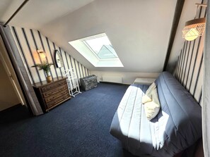 A bedroom with a skylight, a bed, a dresser, and a radiator. - Holiday Home “Les Volets Bleus” with Private Terrace, Garden & Wi-Fi (Pirou)