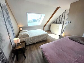 Une chambre avec un puits de lumière, un lit, une table de chevet, une commode et une fenêtre.