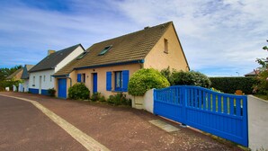 A residential street with houses, a blue gate, and a clear sky.