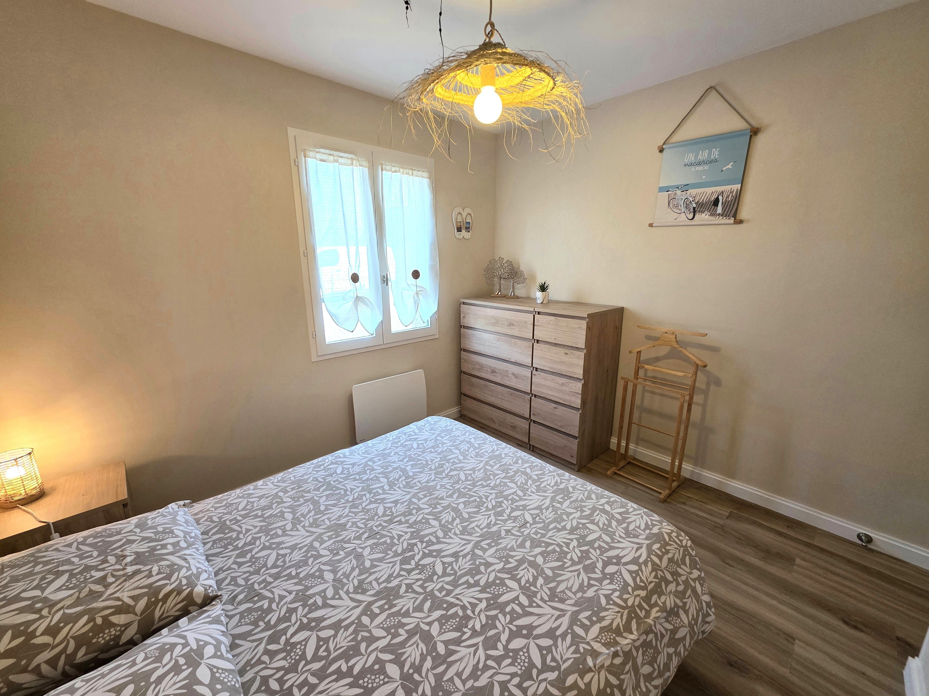 Een slaapkamer met een bed, een kaptafel en een hanglamp.