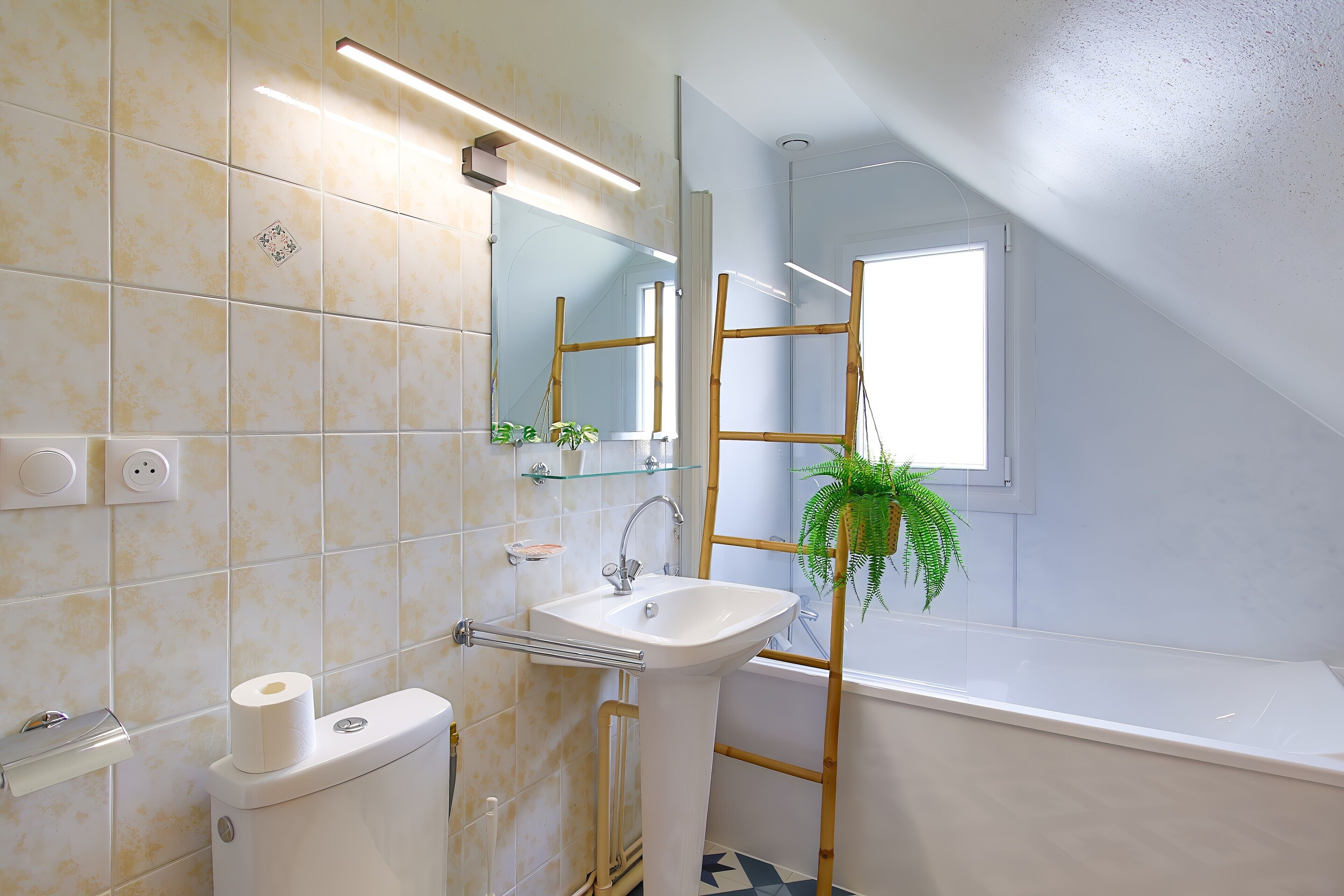 Een badkamer met toilet, wastafel, spiegel en een raam.