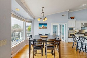 A modern kitchen with a dining area, large windows, and a view of the outdoors. - Oceanfront home with outdoor dining, WIFI, fireplace, gas grill, washer & dryer (Brookings)