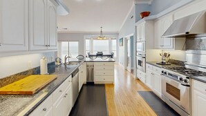 Una cocina moderna con armarios blancos, encimera de granito, electrodomésticos de acero inoxidable y una isla central.