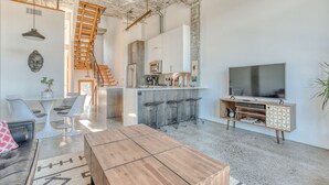 A spacious living area with a wooden coffee table, a sofa, a TV, a kitchen, and a staircase. - Hood River townhouse close to everything with river-view location & rooftop BBQ (Hood River)
