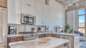 A modern kitchen with a central island, stainless steel appliances, and a view of the city. - Hood River townhouse close to everything with river-view location & rooftop BBQ (Hood River)