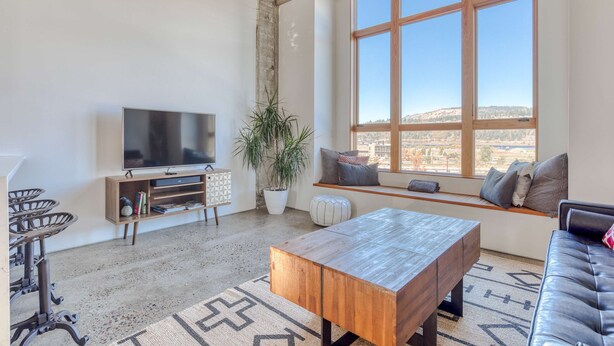 A living room with a large window, a TV, a wooden coffee table, and a sofa. - Hood River townhouse close to everything with river-view location & rooftop BBQ (Hood River)