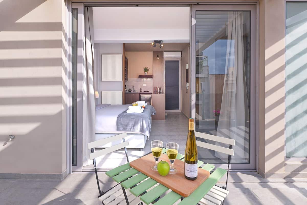 A balcony with a table, a bottle of wine, glasses, and an apple.