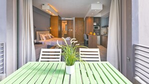 Um interior moderno com área de jantar, quarto com cama e cozinha compacta.