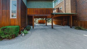 En modern byggnad med en överbyggd gångväg, träpanel och en gångstig av tegelstenar.