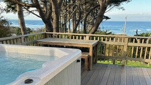Un bain à remous sur une terrasse en bois, avec vue sur l’océan.