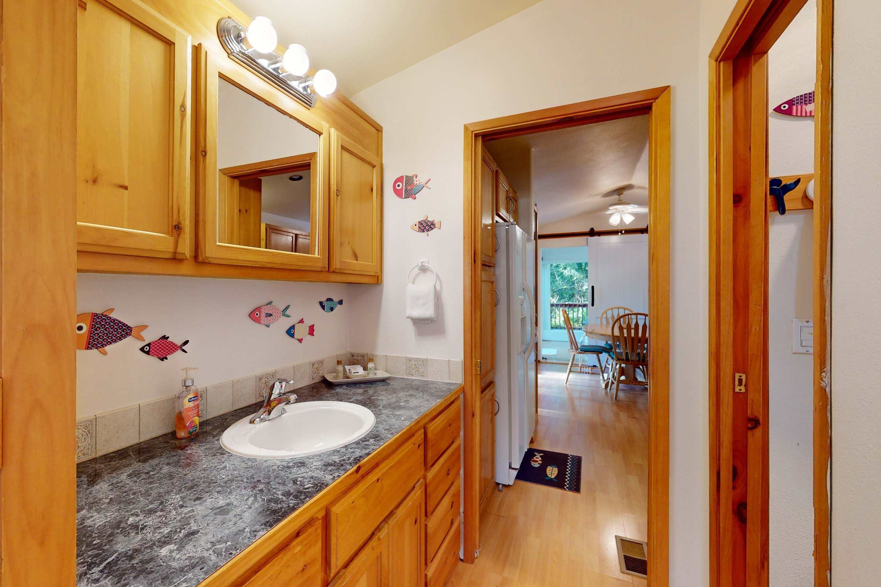 A bathroom with wooden cabinets, a sink, and a mirror. There are fish decorations on the wall.