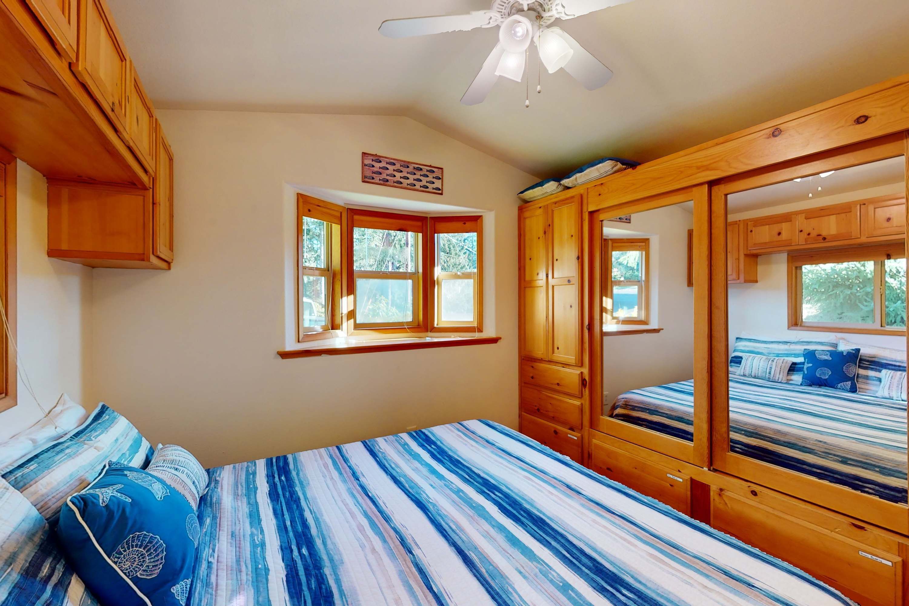 Ein Schlafzimmer mit einem großen Bett, Holzschränken, einem Deckenventilator und einem Fenster.