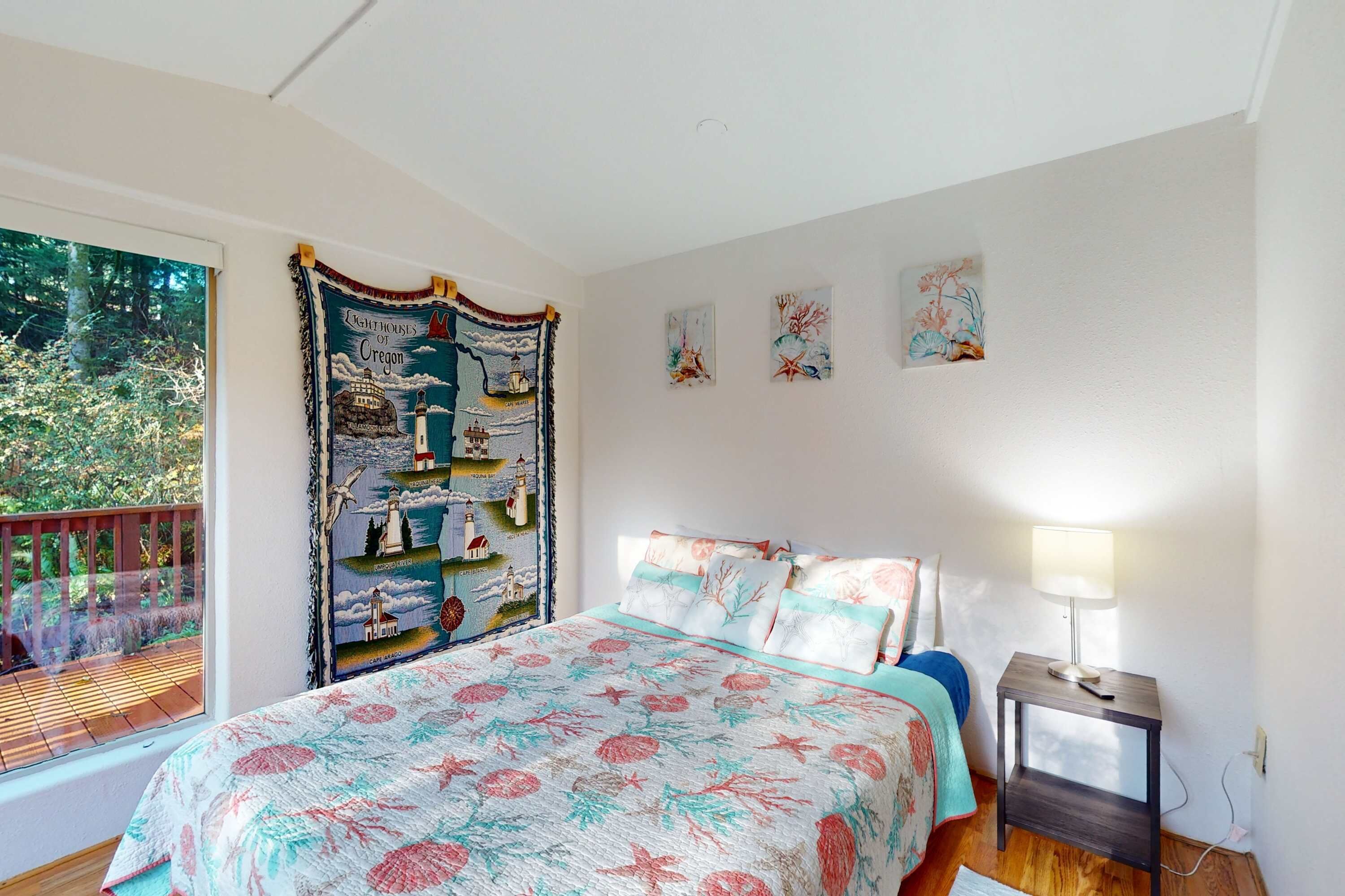 A bedroom with a large bed, a nightstand, a window with a view of trees, and a wall with artwork.