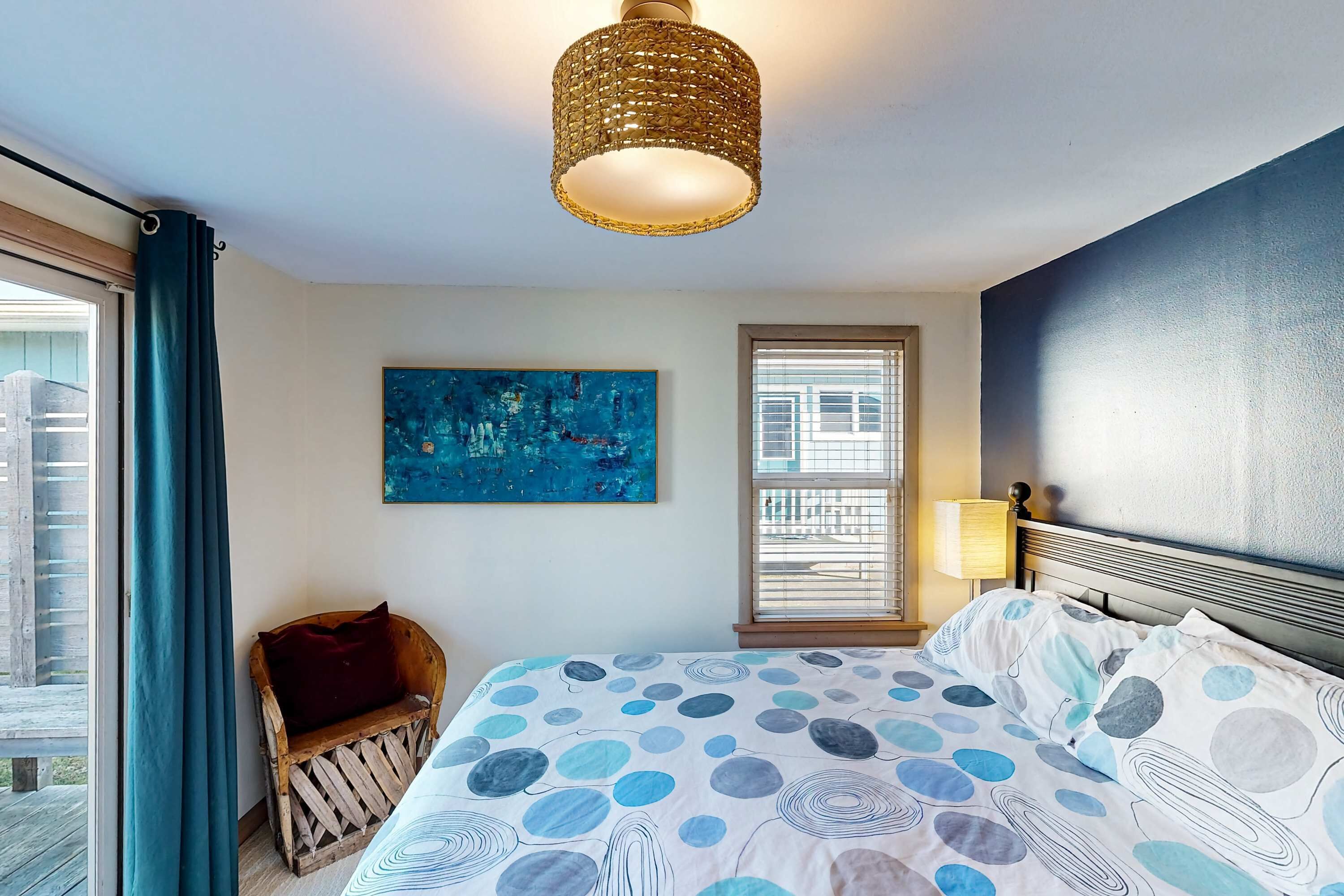 Un dormitorio con cama, ventana, cuadro y lámpara.