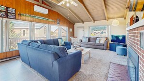 Ein geräumiges Wohnzimmer mit einem großen blauen Sofa, einem grauen Sofa, einem Fernseher und einem Kamin.