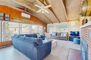 Ein geräumiges Wohnzimmer mit einem großen blauen Sofa, einem grauen Sofa, einem Fernseher und einem Kamin.