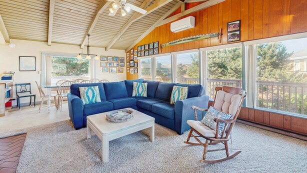 Ein Wohnzimmer mit blauem Ecksofa, einem Schaukelstuhl, einem Couchtisch und einem Deckenventilator.