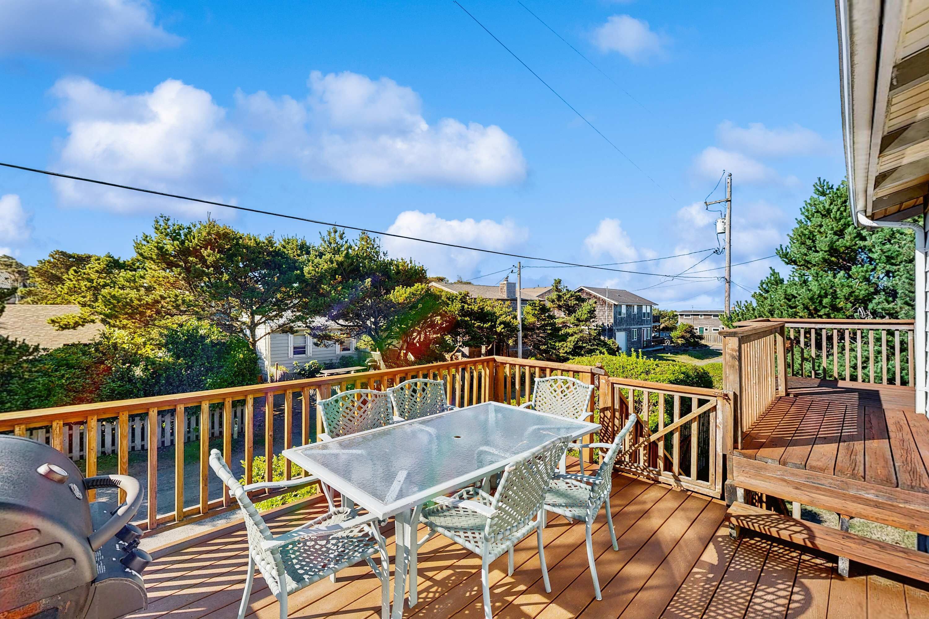 A wooden deck with a glass table and chairs, surrounded by a wooden railing.