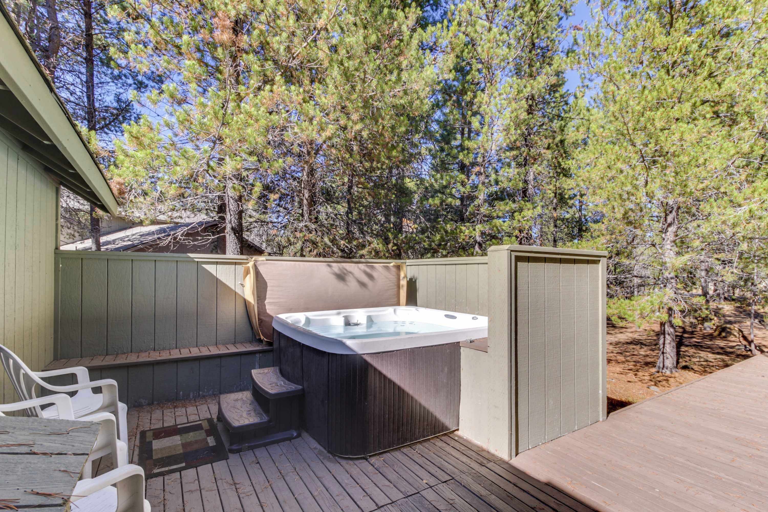 An outdoor hot tub area with a wooden deck, seating, and a wooden fence.