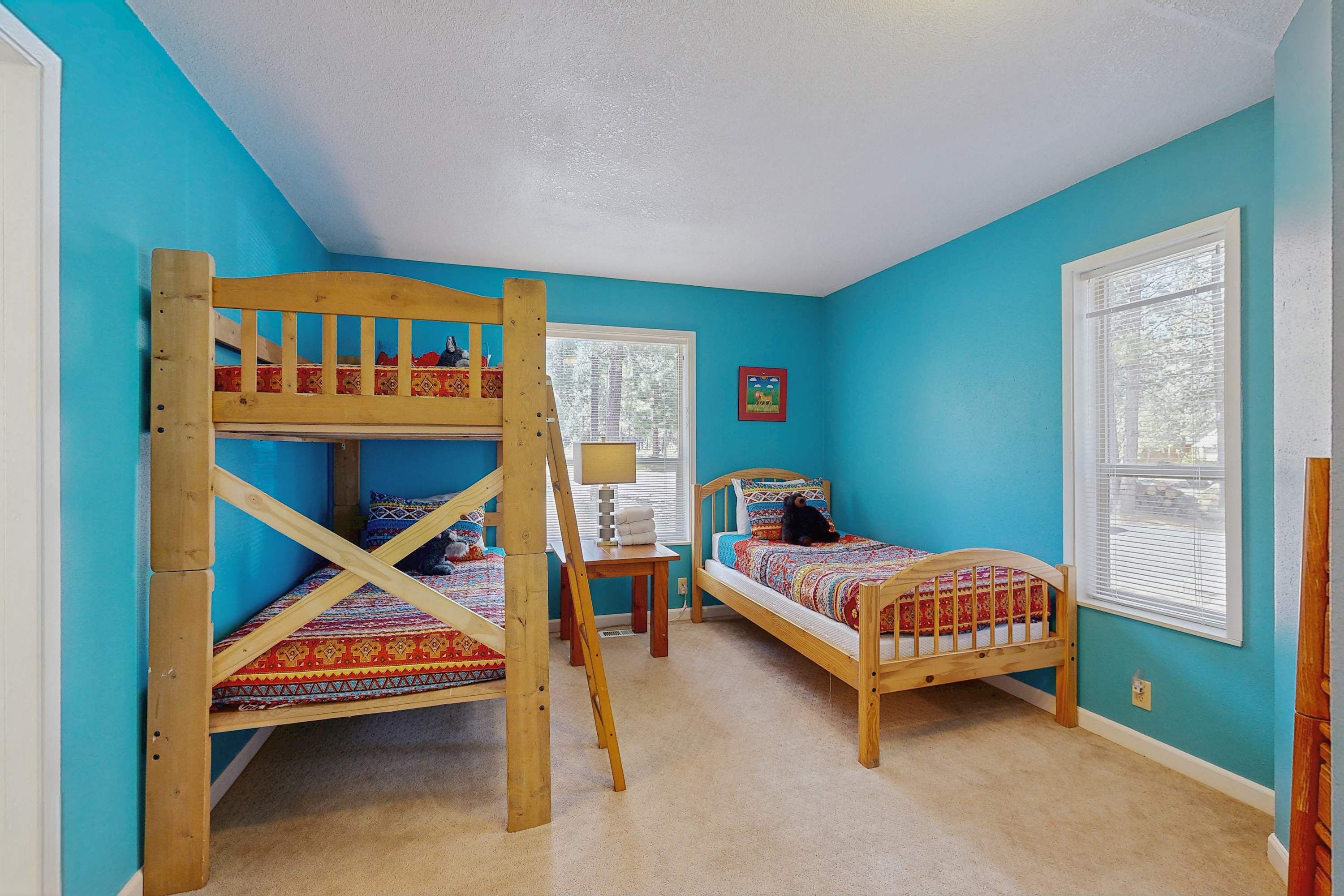 A room with two bunk beds, a small table, and a window.