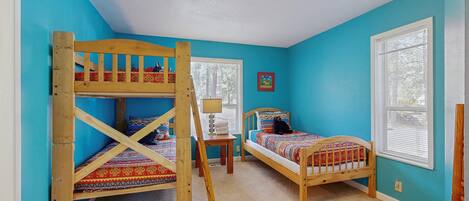 A room with two bunk beds, a small table, and a window.