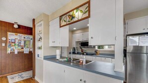 Eine Küche mit weißen Schränken, einem Edelstahlkühlschrank und einer blauen Arbeitsplatte.