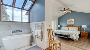 A bathroom with a freestanding bathtub, a towel rack, and a window with a skylight.