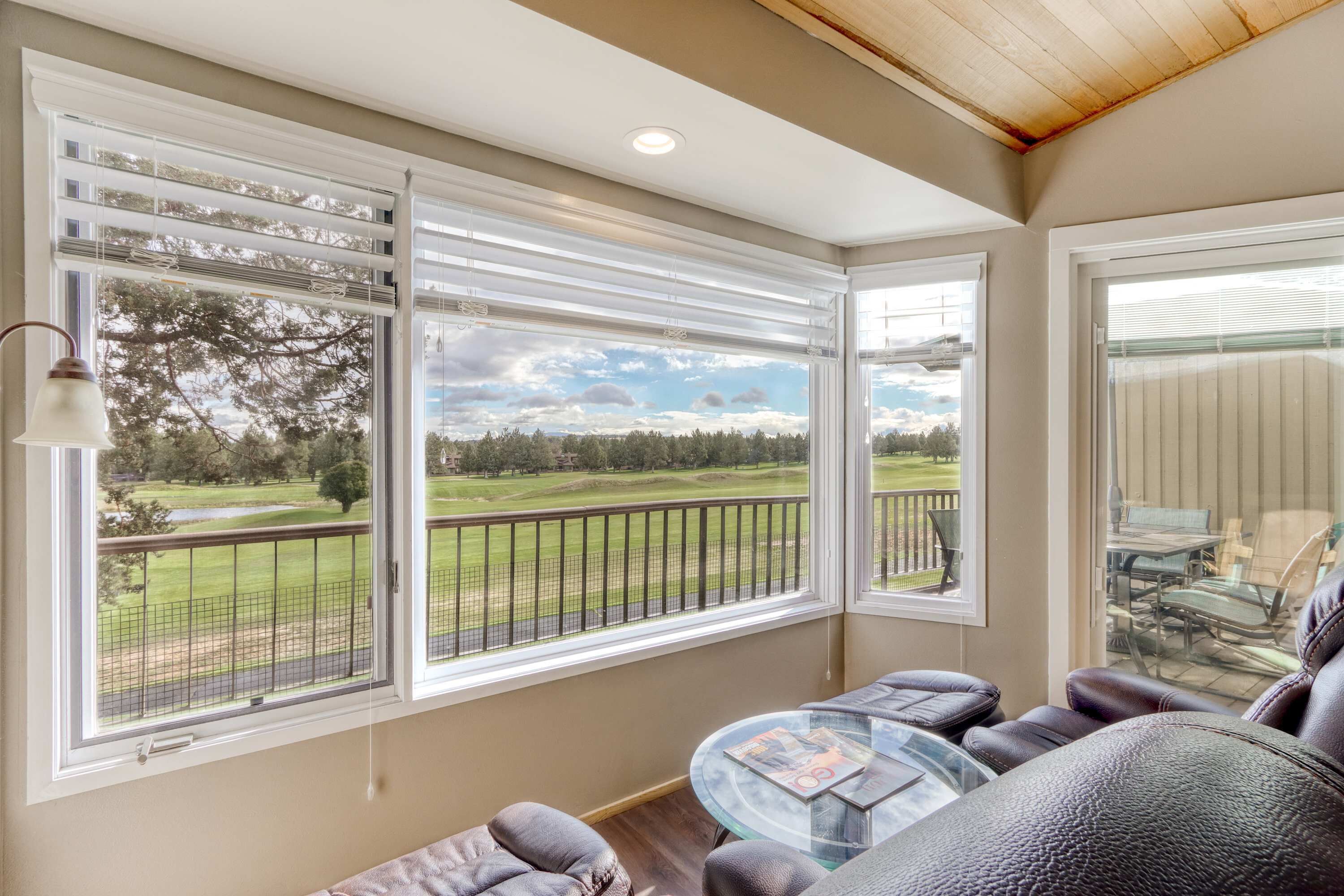 A room with a large window, a glass table, and leather seating.