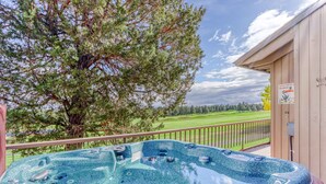 A hot tub on a balcony with a view of a golf course.