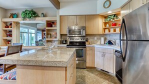 A modern kitchen with granite countertops, stainless steel appliances, wooden cabinets, and a large island.