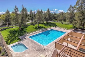 A rectangular swimming pool with a diving board, surrounded by a grassy area and trees.