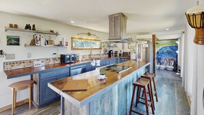 Una cucina moderna con isola centrale, sgabelli da bar e vista sull'oceano attraverso una finestra.