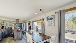 Una cucina moderna con isola centrale, sgabelli da bar bianchi e un tavolo da pranzo con sedie.