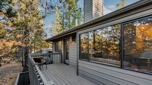 A modern house with a deck, large windows, and a chimney. - Inviting home with deck, gas grill, hot tub, pools, and SHARC passes (Sunriver)