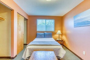 Une chambre à coucher avec un lit, une table de chevet, une fenêtre avec des stores et un tableau au mur.