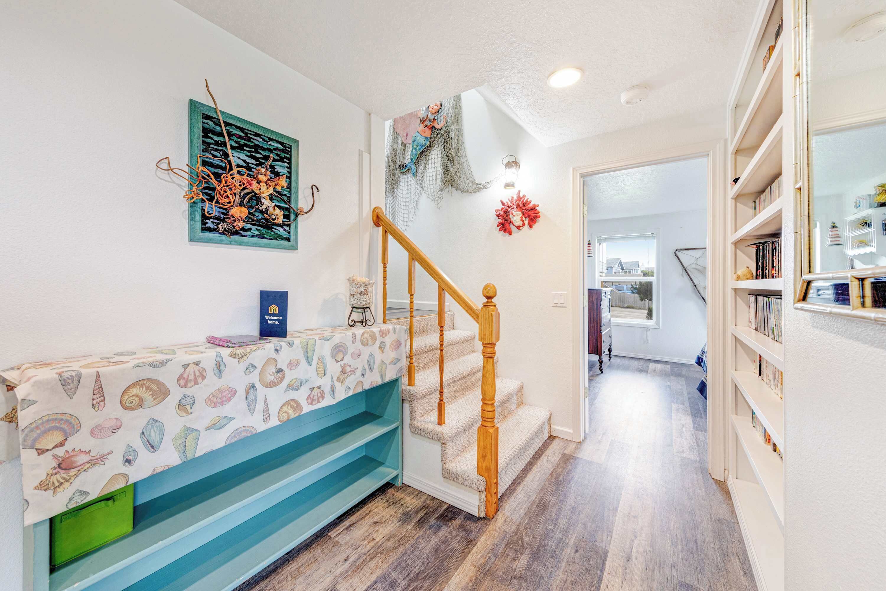 A staircase with a wooden handrail, a bench with a patterned tablecloth, and a wall with a decorative piece.