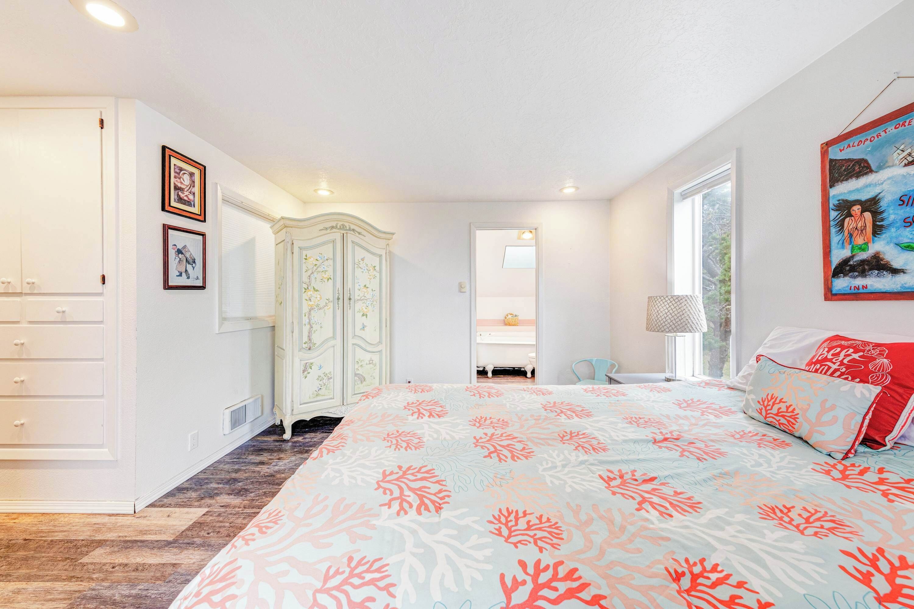 A bedroom with a bed, a wardrobe, a dresser, a mirror, and a window.
