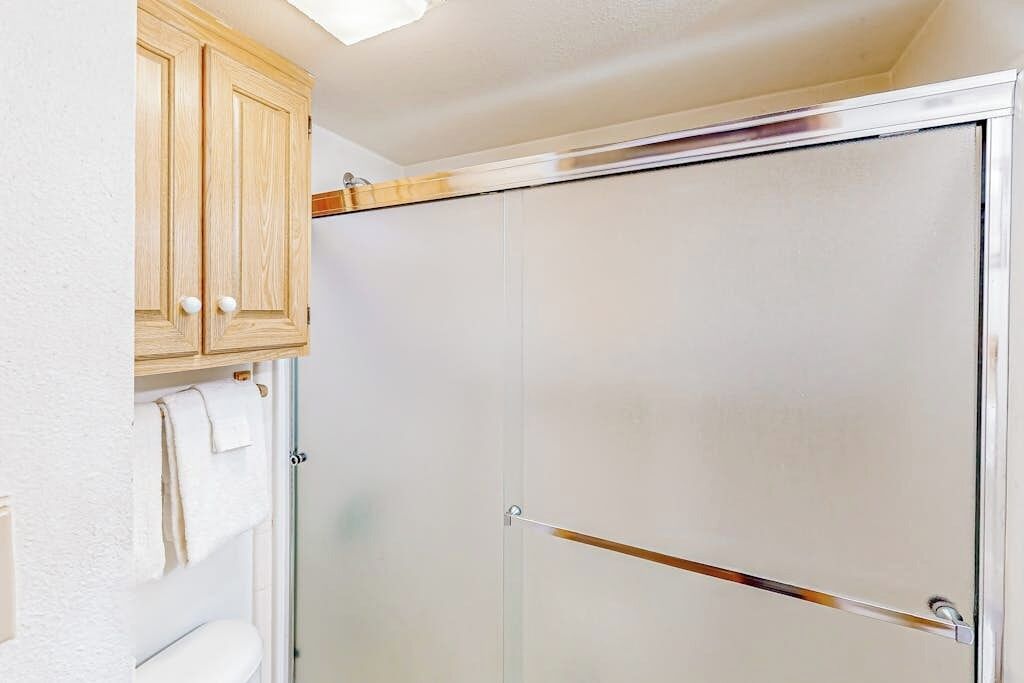 A bathroom with a shower enclosure, a wooden cabinet, and a towel rack.