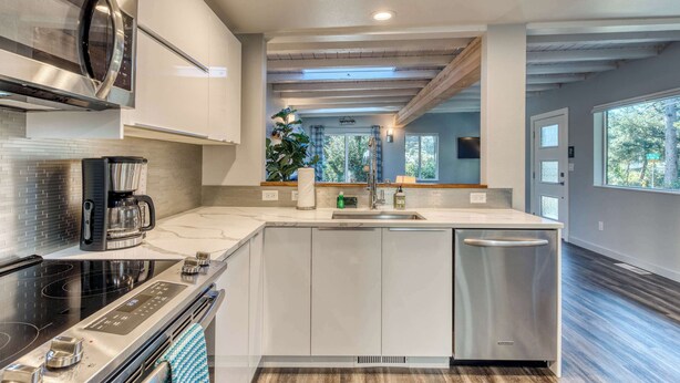A modern kitchen with stainless steel appliances, a built-in oven, and a dishwasher. - Stunning new home with furnished deck & easy beach access (Florence)